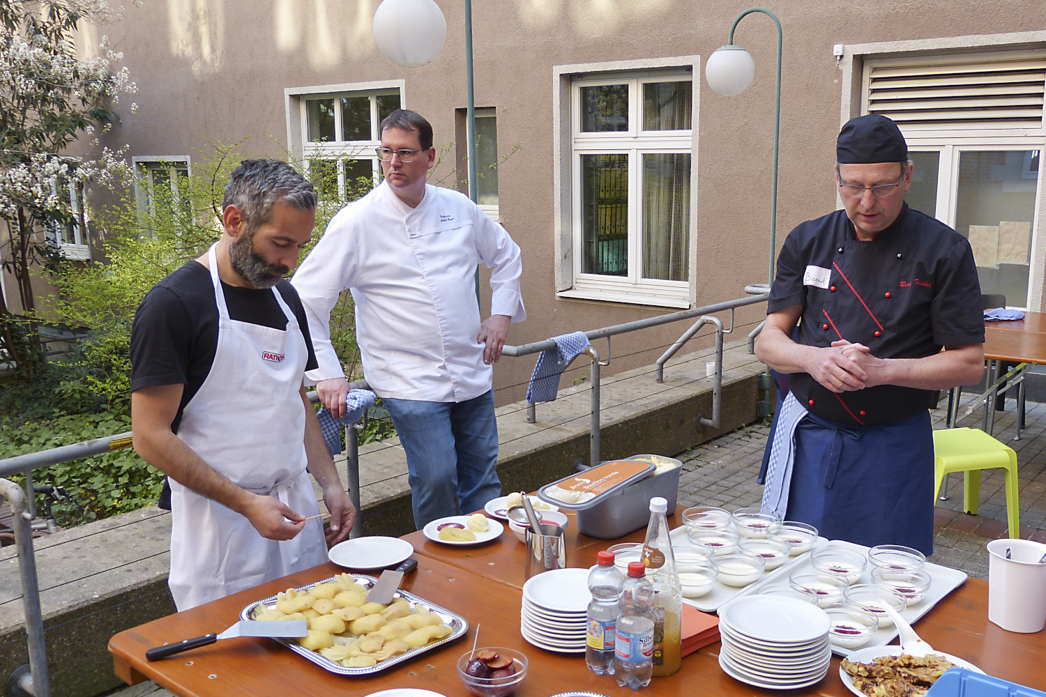 Bernd Fischer von der Stadtmission betrachtet mit seinem Assistenten und einem Teilnehmer das Ergebnis des gemeinsamen Kochens